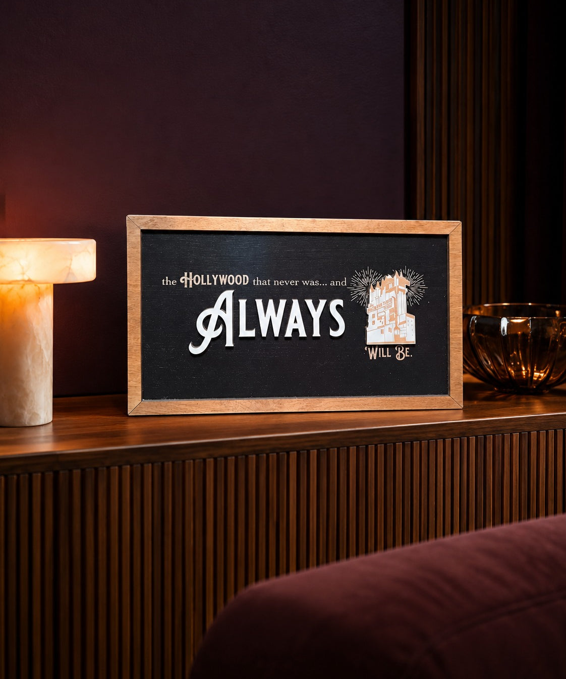 The Hollywood That Never Was tower hotel framed wood sign styled on a fluted walnut console in a screening lounge