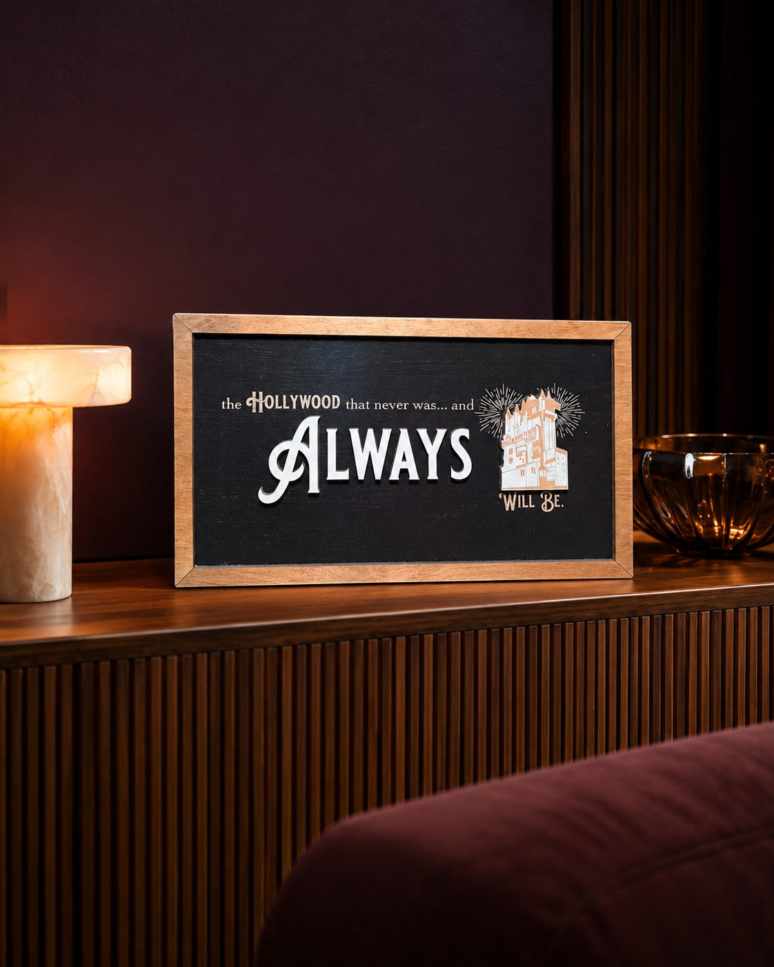 The Hollywood That Never Was tower hotel framed wood sign styled on a fluted walnut console in a screening lounge
