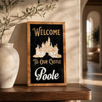 Welcome To Our Castle personalized framed wood sign styled on a walnut shelf in a warm foyer