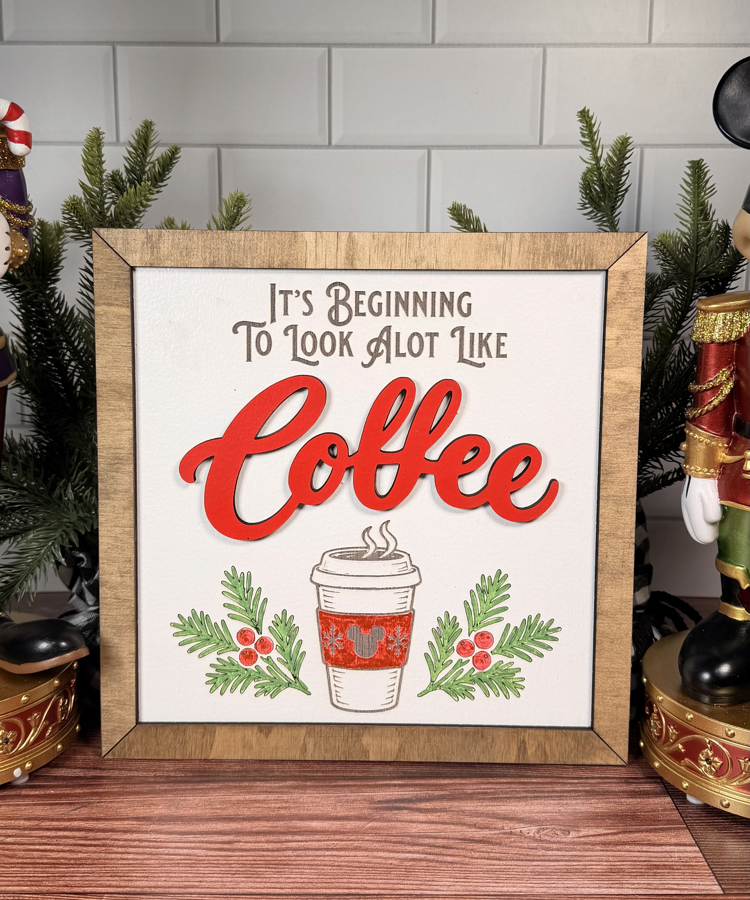 It's Beginning to Look a Lot Like Coffee square Christmas sign with red layered Coffee lettering, a takeaway cup, evergreen sprigs and a brown wood frame.