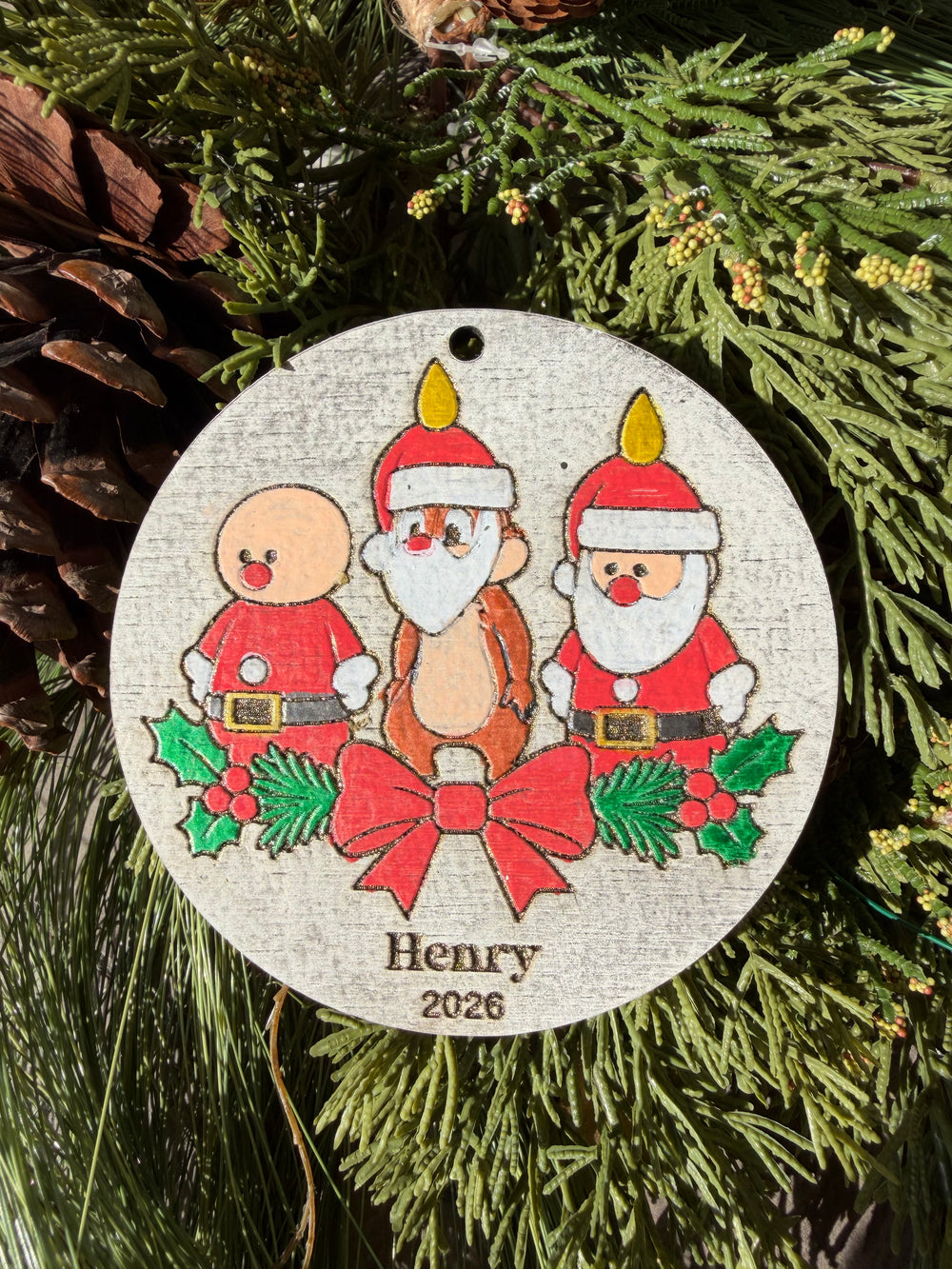 Finished hand-painted Dale’s Candlelight Christmas Ornament on evergreen greenery. Personal name and year shown are sample personalization.