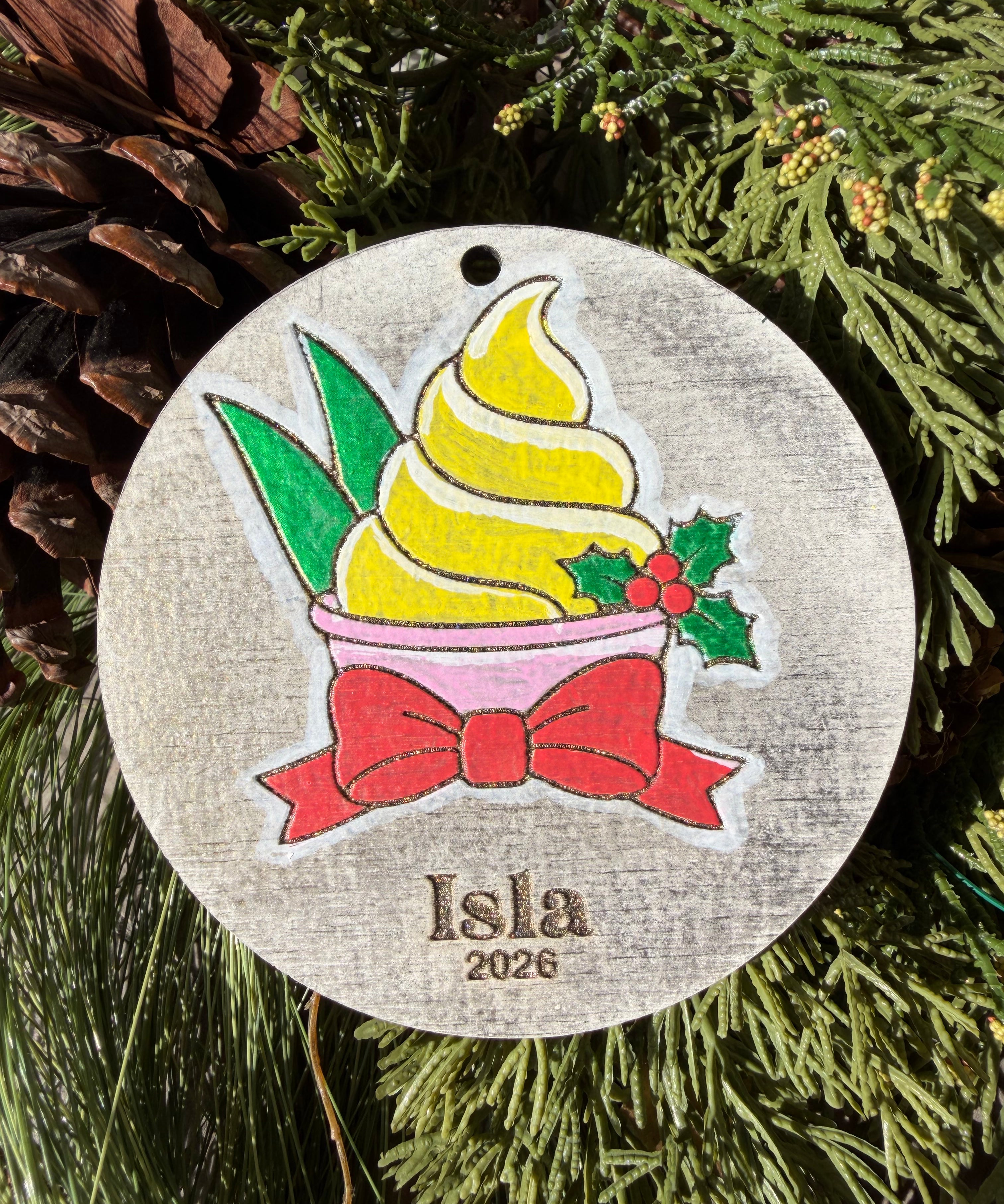 Finished hand-painted Pineapple Swirl Christmas Ornament on evergreen greenery. Personal name and year shown are sample personalization.