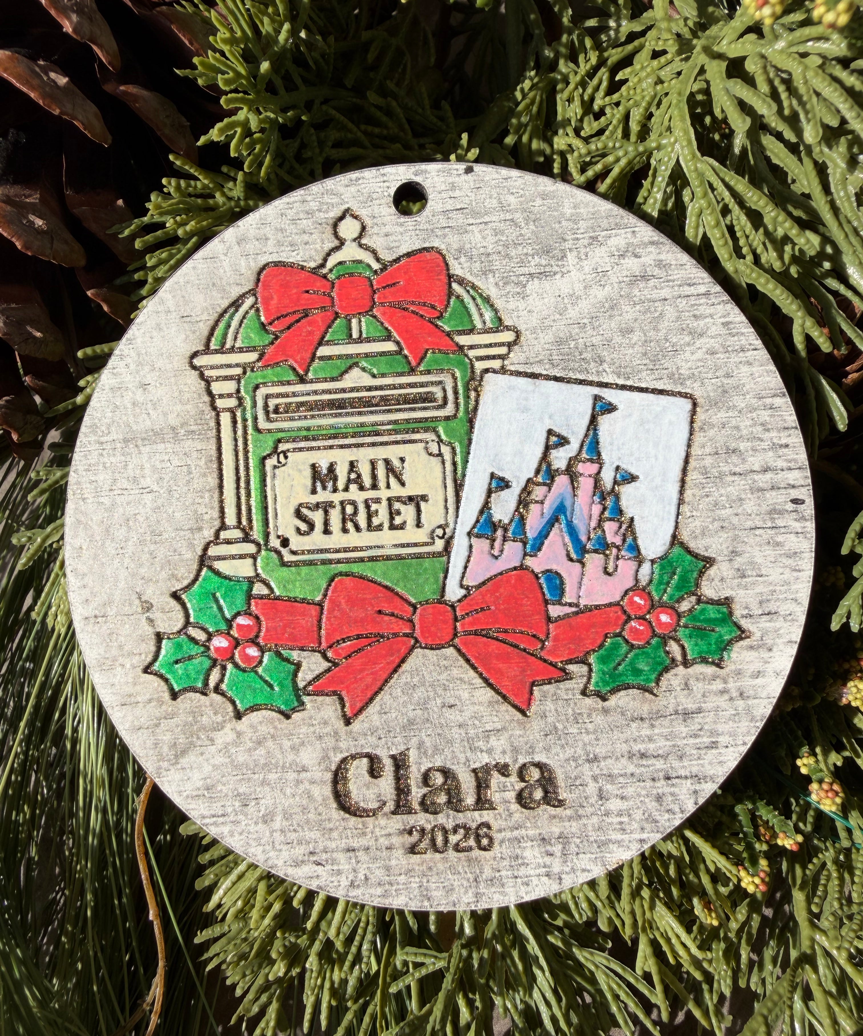 Finished hand-painted Main Street Mailbox Christmas Ornament on evergreen greenery. Personal name and year shown are sample personalization.