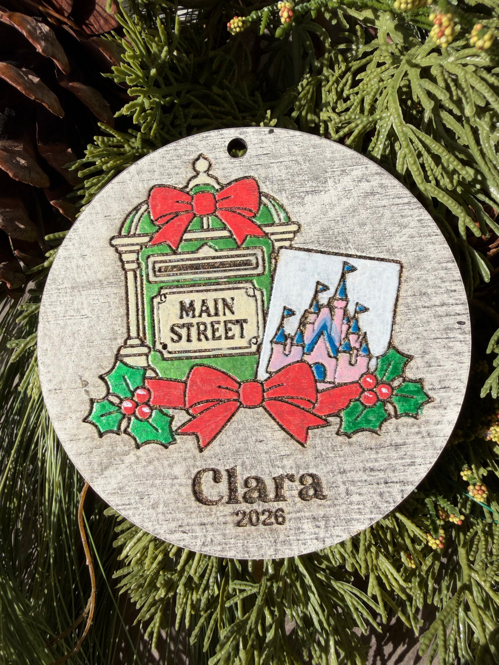 Finished hand-painted Main Street Mailbox Christmas Ornament on evergreen greenery. Personal name and year shown are sample personalization.