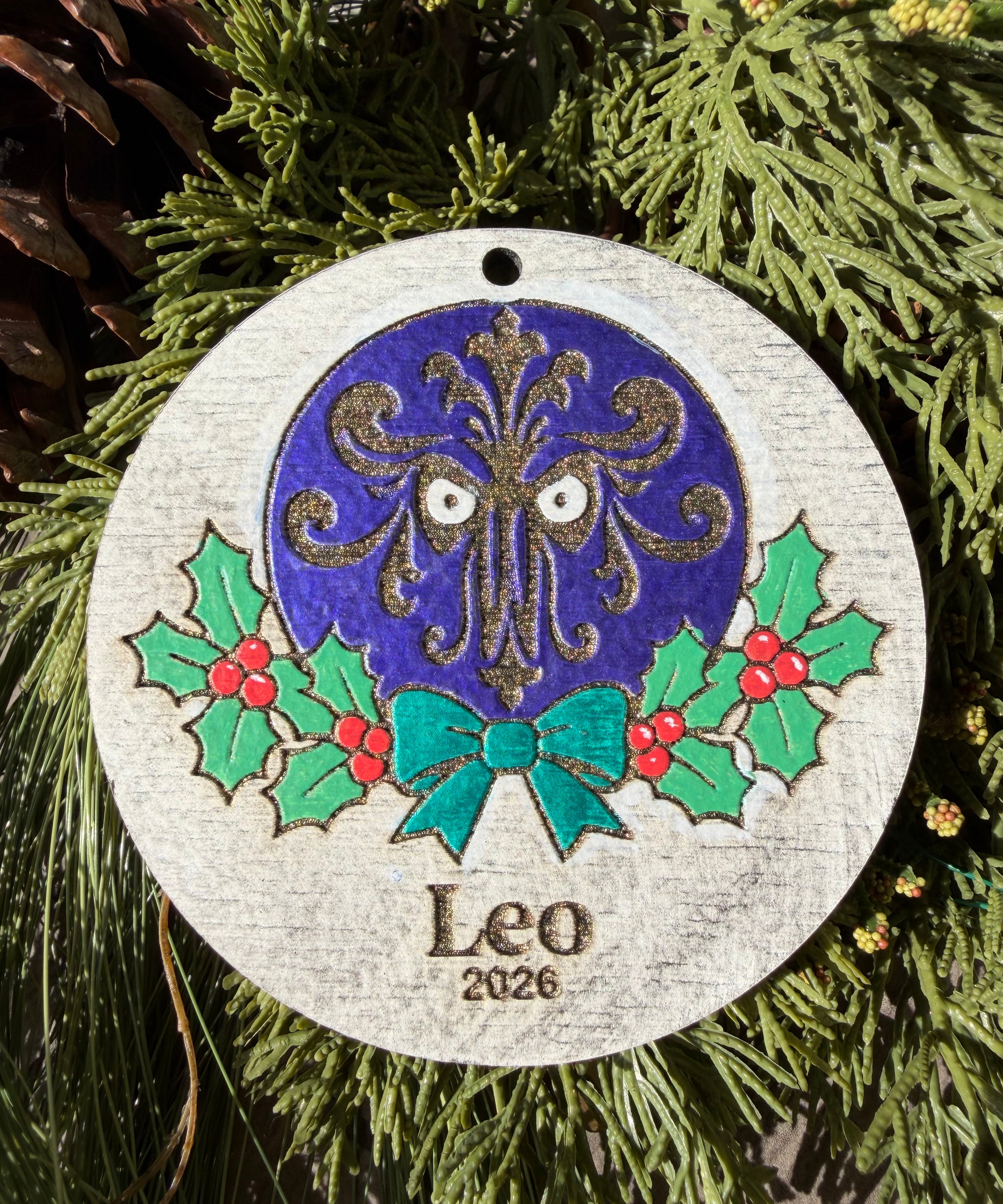 Finished hand-painted Haunted Mansion Wallpaper Christmas Ornament on evergreen greenery. Personal name and year shown are sample personalization.
