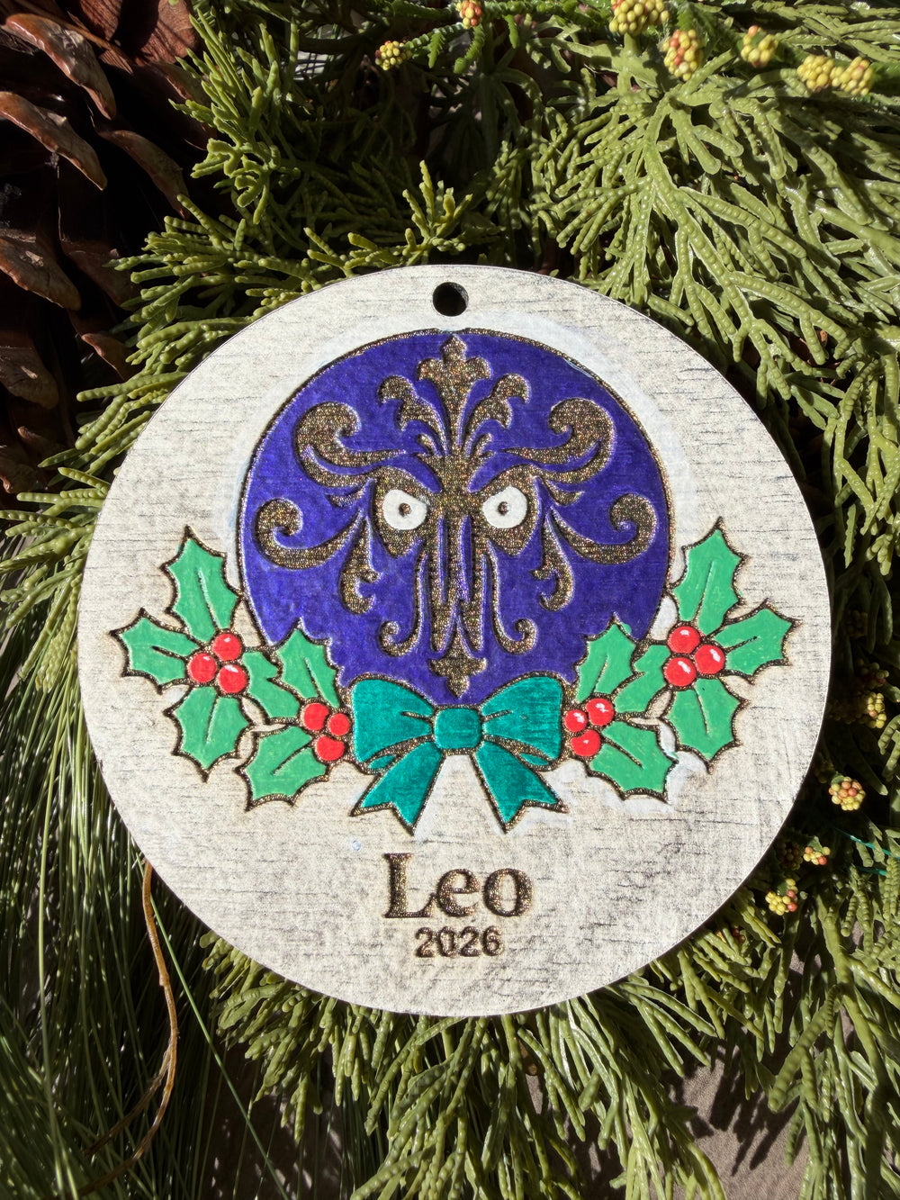 Finished hand-painted Haunted Mansion Wallpaper Christmas Ornament on evergreen greenery. Personal name and year shown are sample personalization.