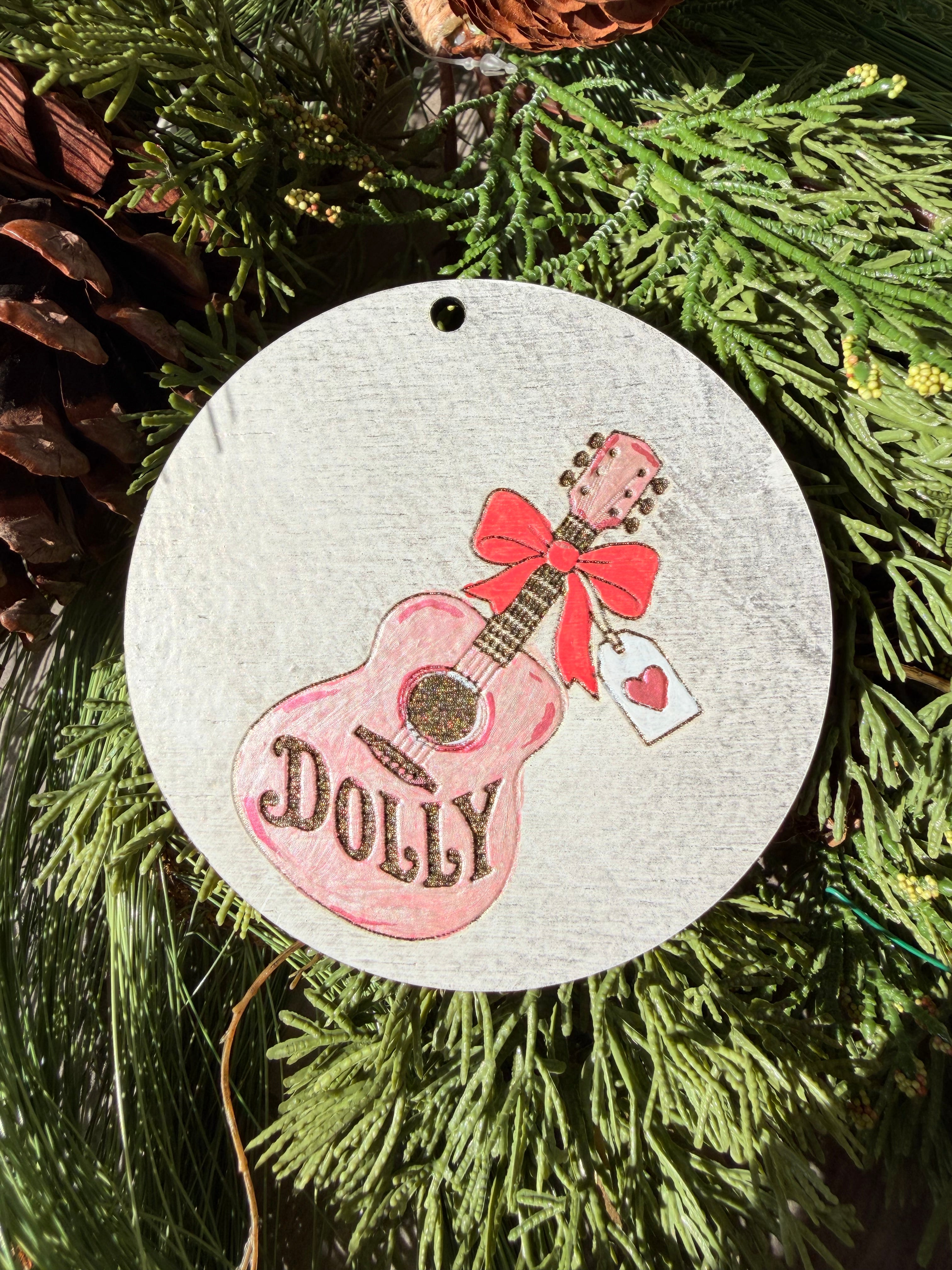 Finished hand-painted Dolly Pink Guitar & Bow on evergreen greenery.
