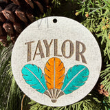 Finished hand-painted Taylor Feather Trio on evergreen greenery.