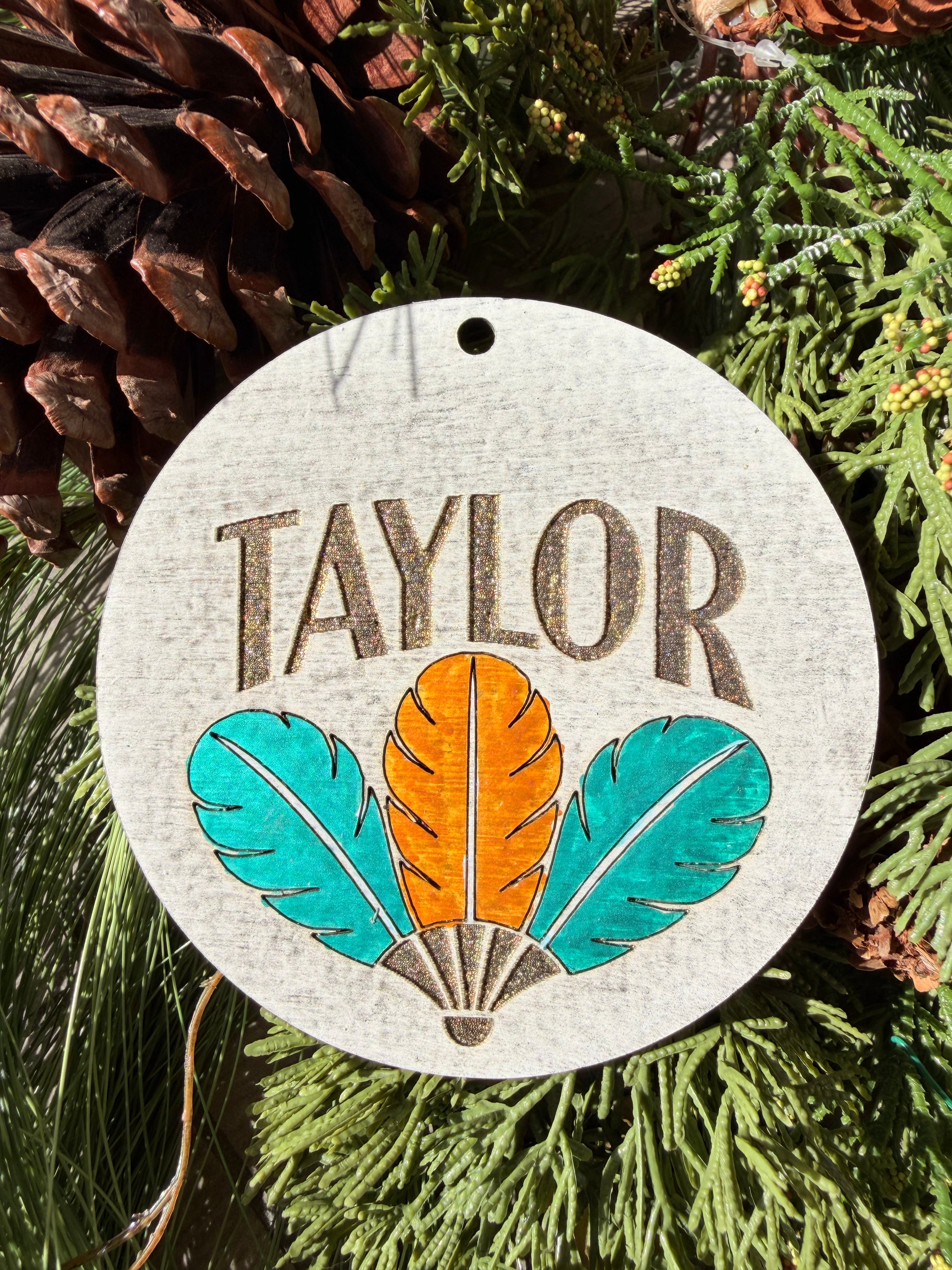 Finished hand-painted Taylor Feather Trio on evergreen greenery.