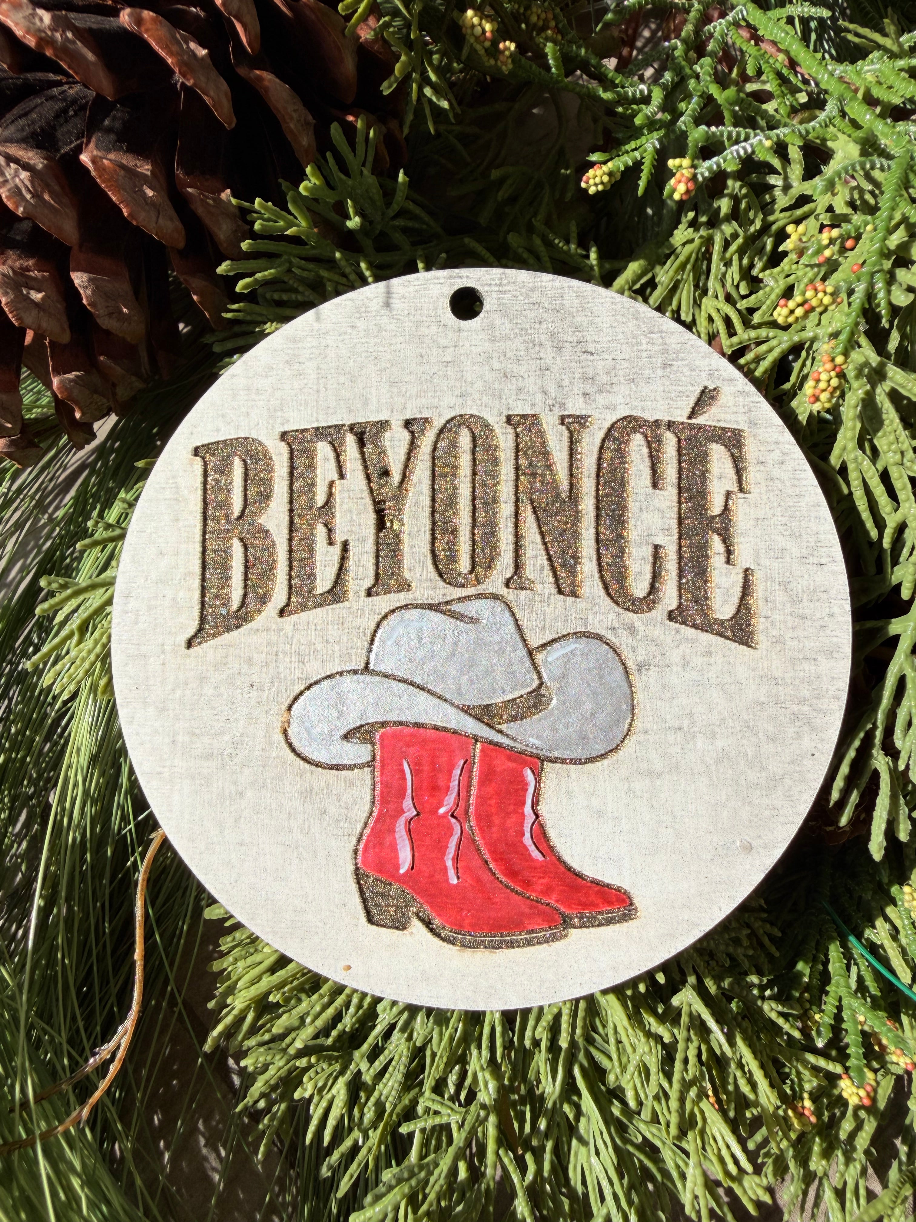 Finished hand-painted Beyoncé Cowboy Boots & Hat on evergreen greenery.