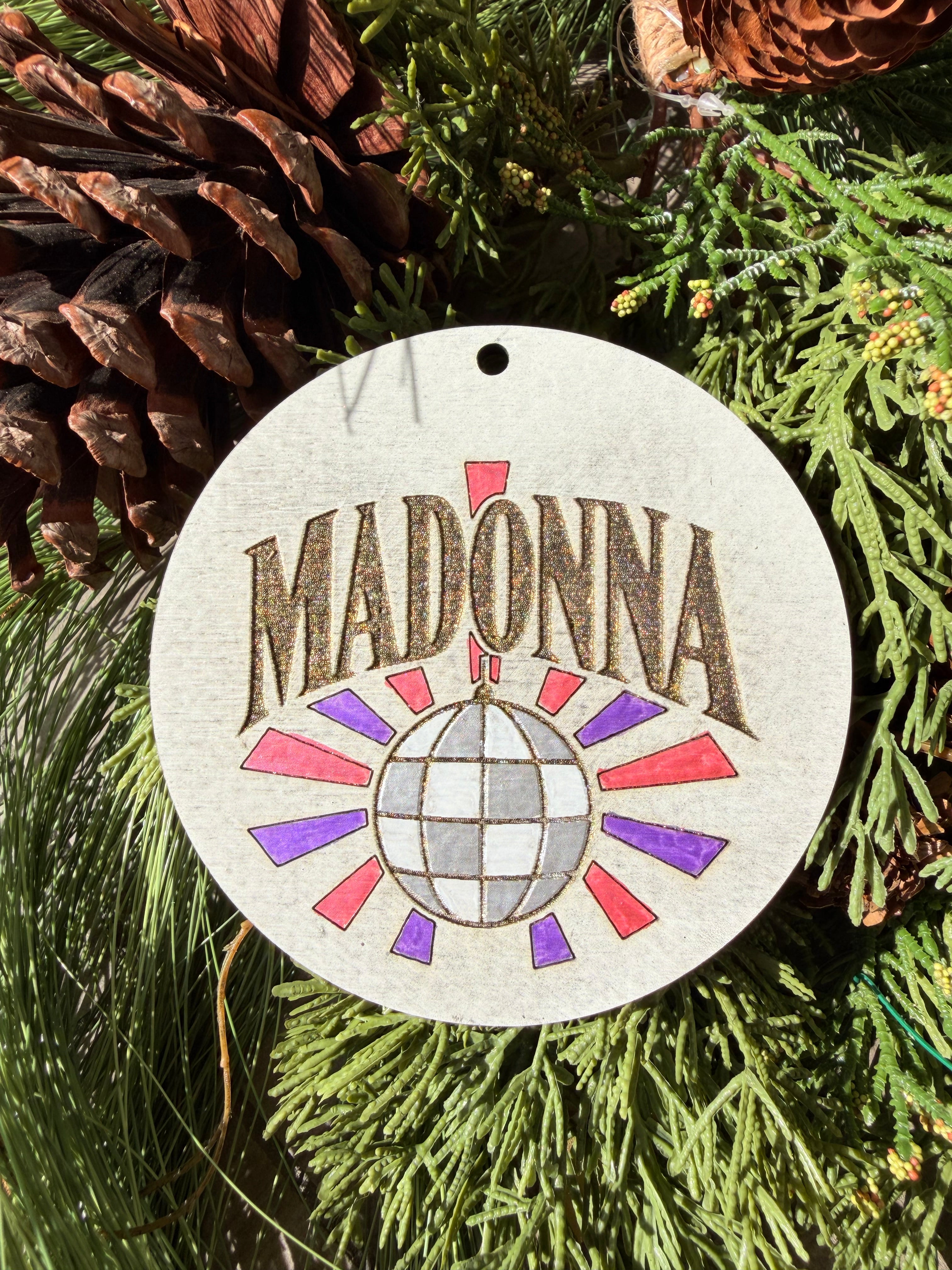 Finished hand-painted Madonna Disco Ball on evergreen greenery.