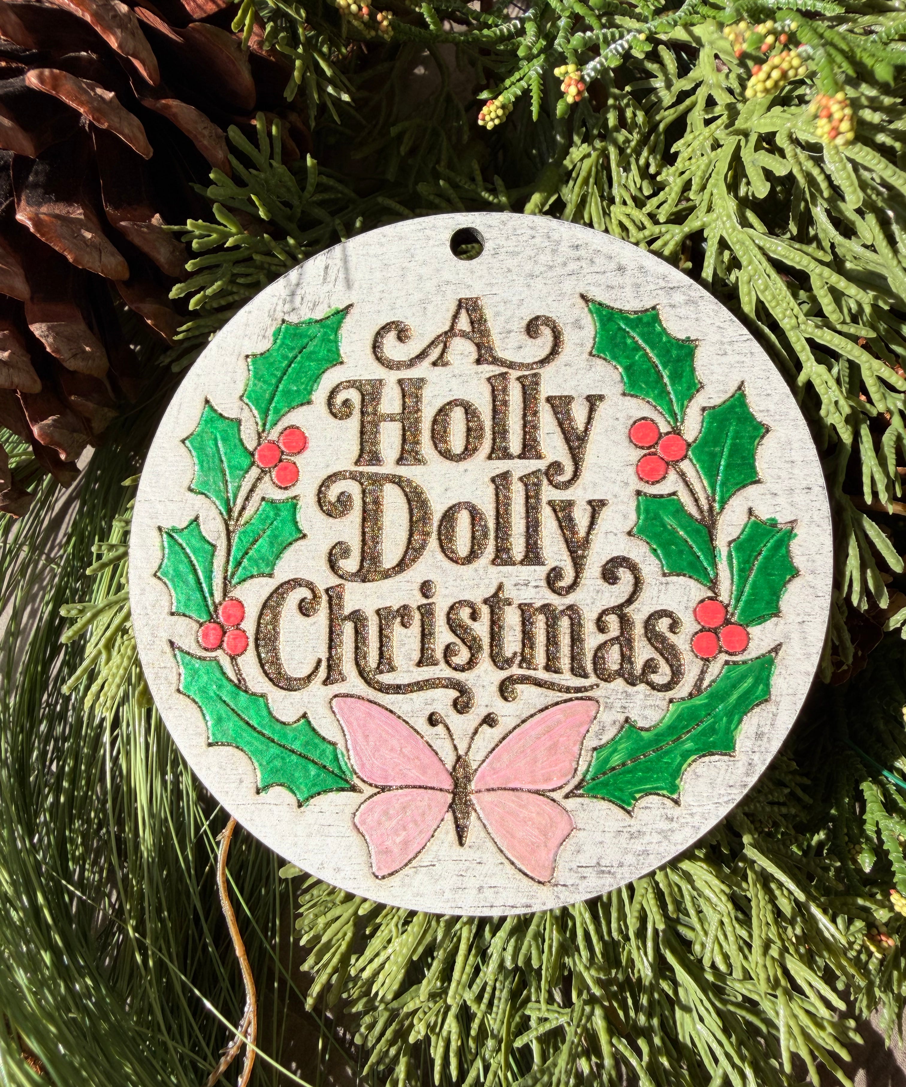 Finished hand-painted A Holly Dolly Christmas Wreath on evergreen greenery.
