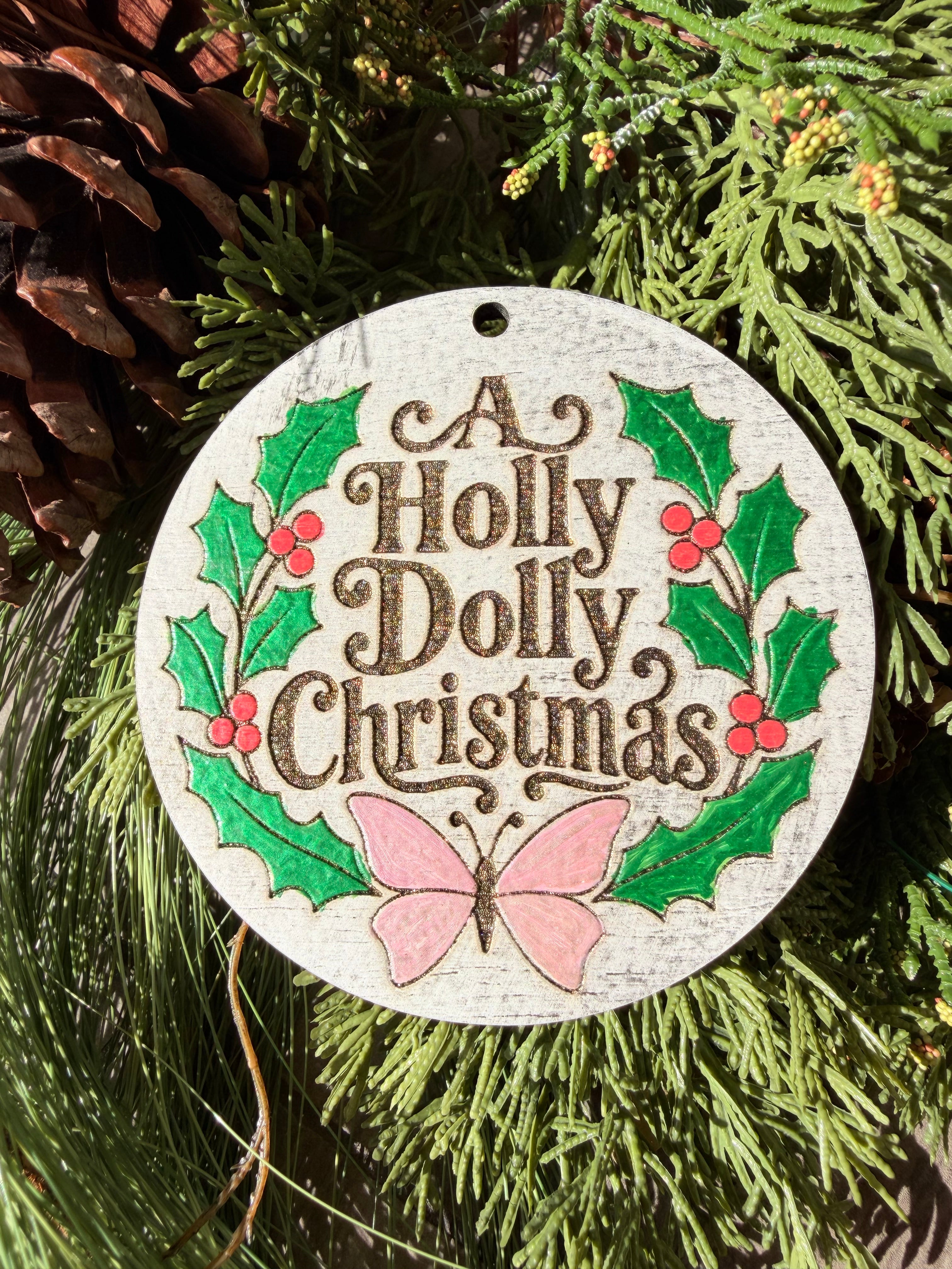 Finished hand-painted A Holly Dolly Christmas Wreath on evergreen greenery.