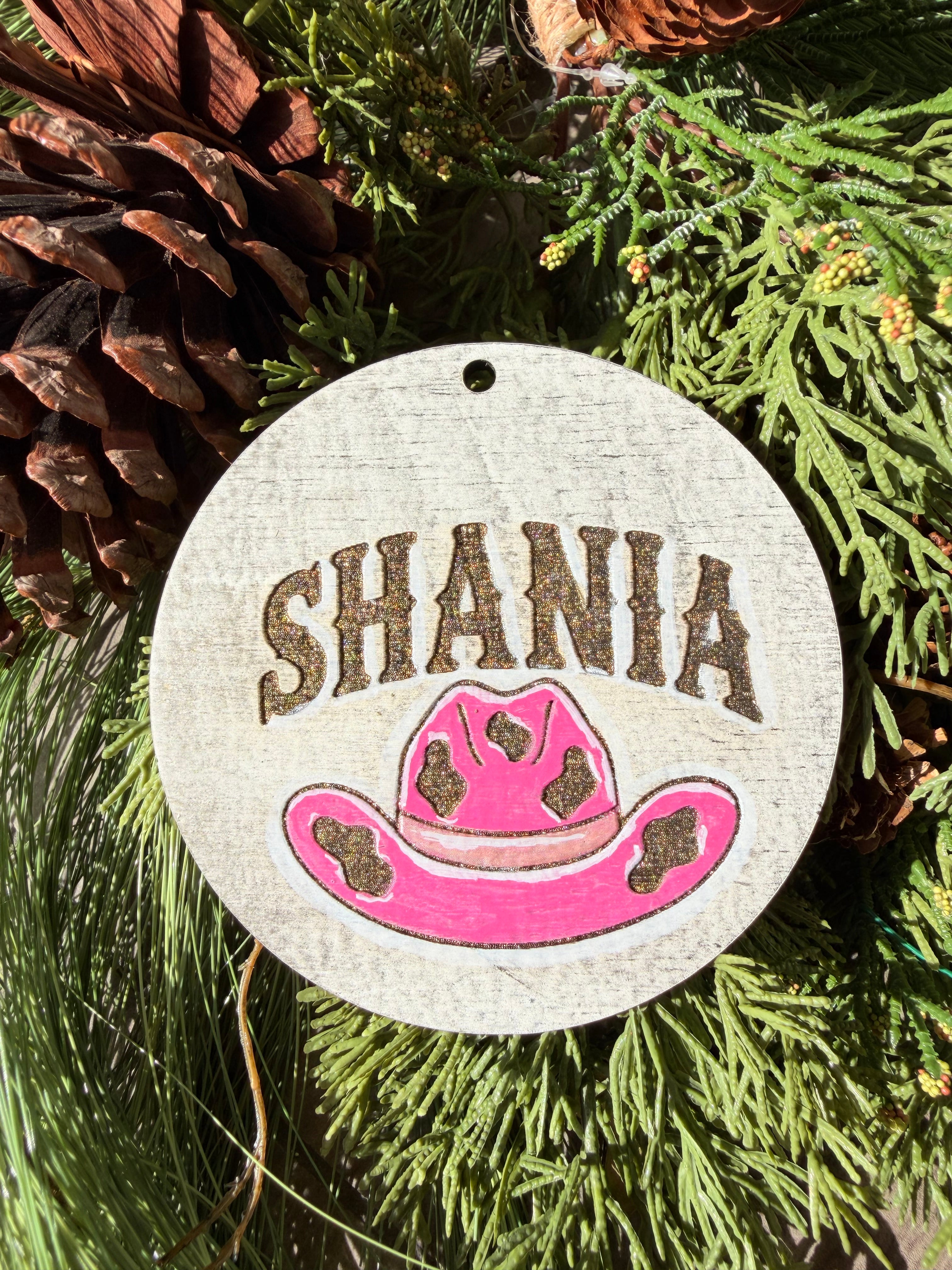 Finished hand-painted Shania Pink Cowboy Hat on evergreen greenery.