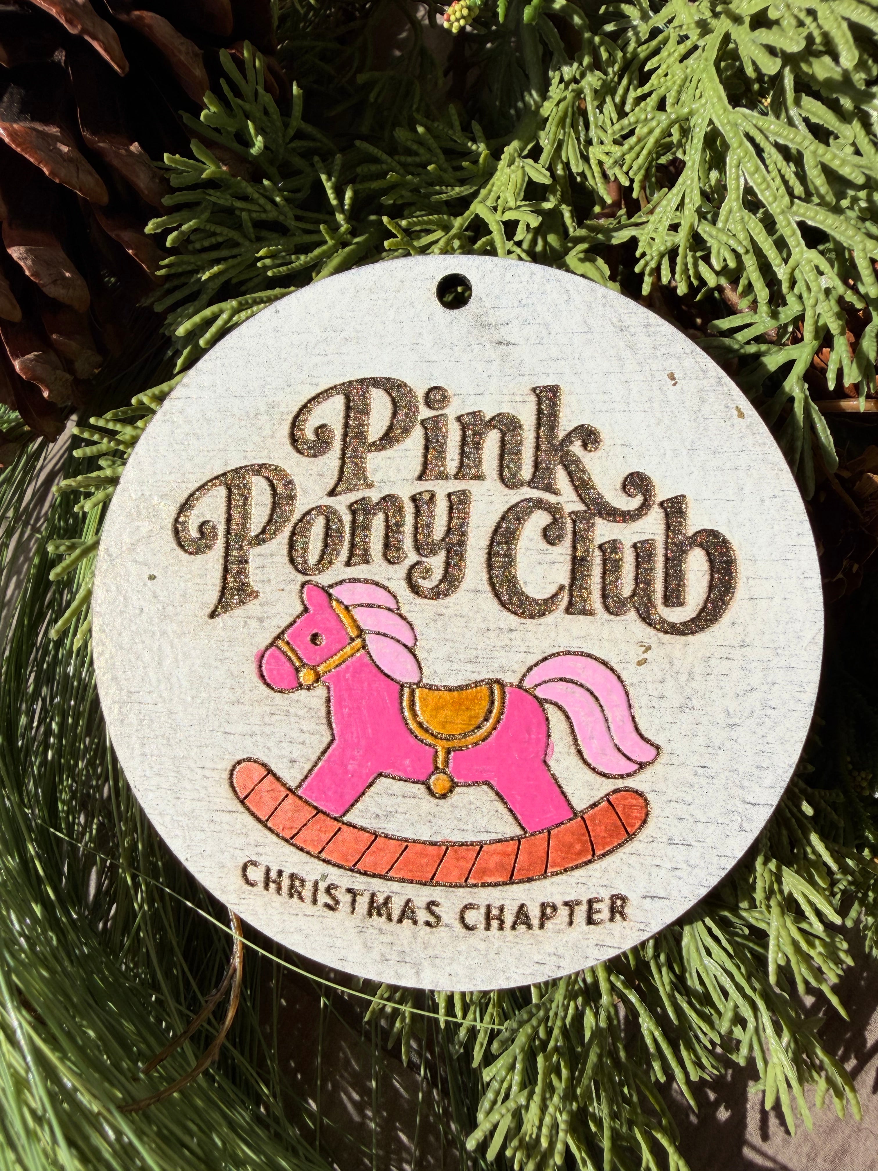 Finished hand-painted Pink Pony Club Christmas Chapter on evergreen greenery.