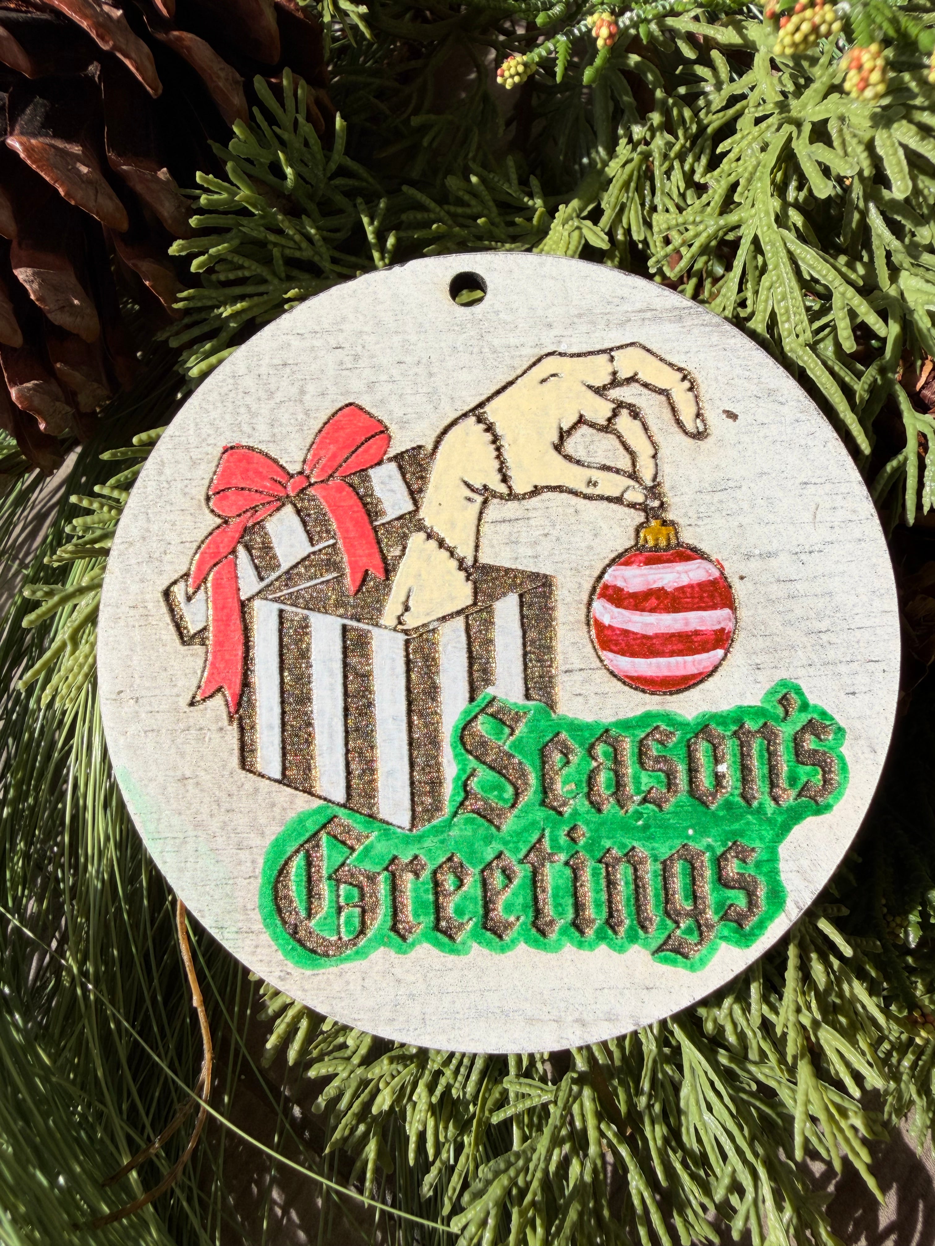Finished hand-painted Season’s Greetings Striped Gift on evergreen greenery.