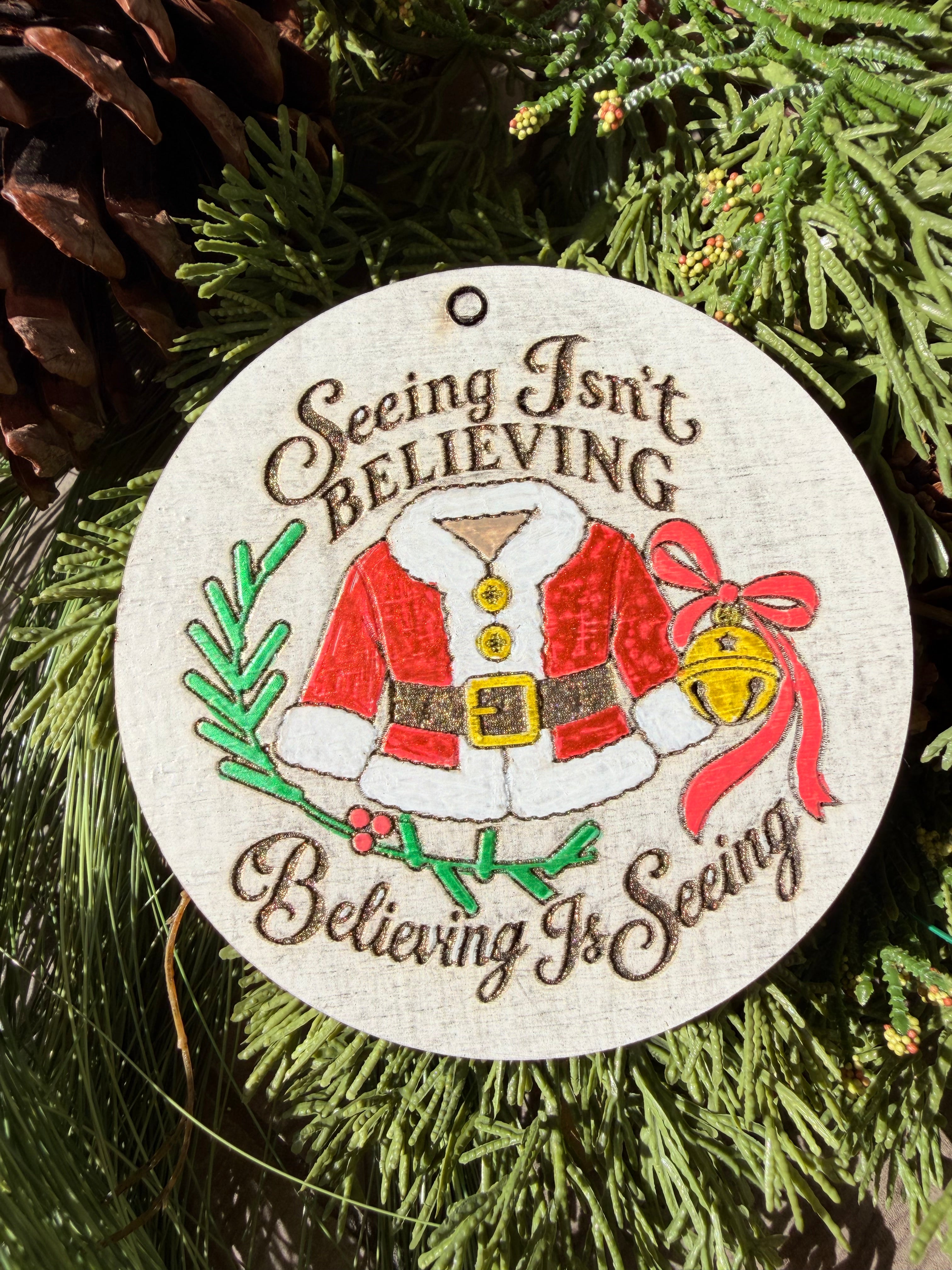 Finished hand-painted Seeing Isn’t Believing on evergreen greenery.