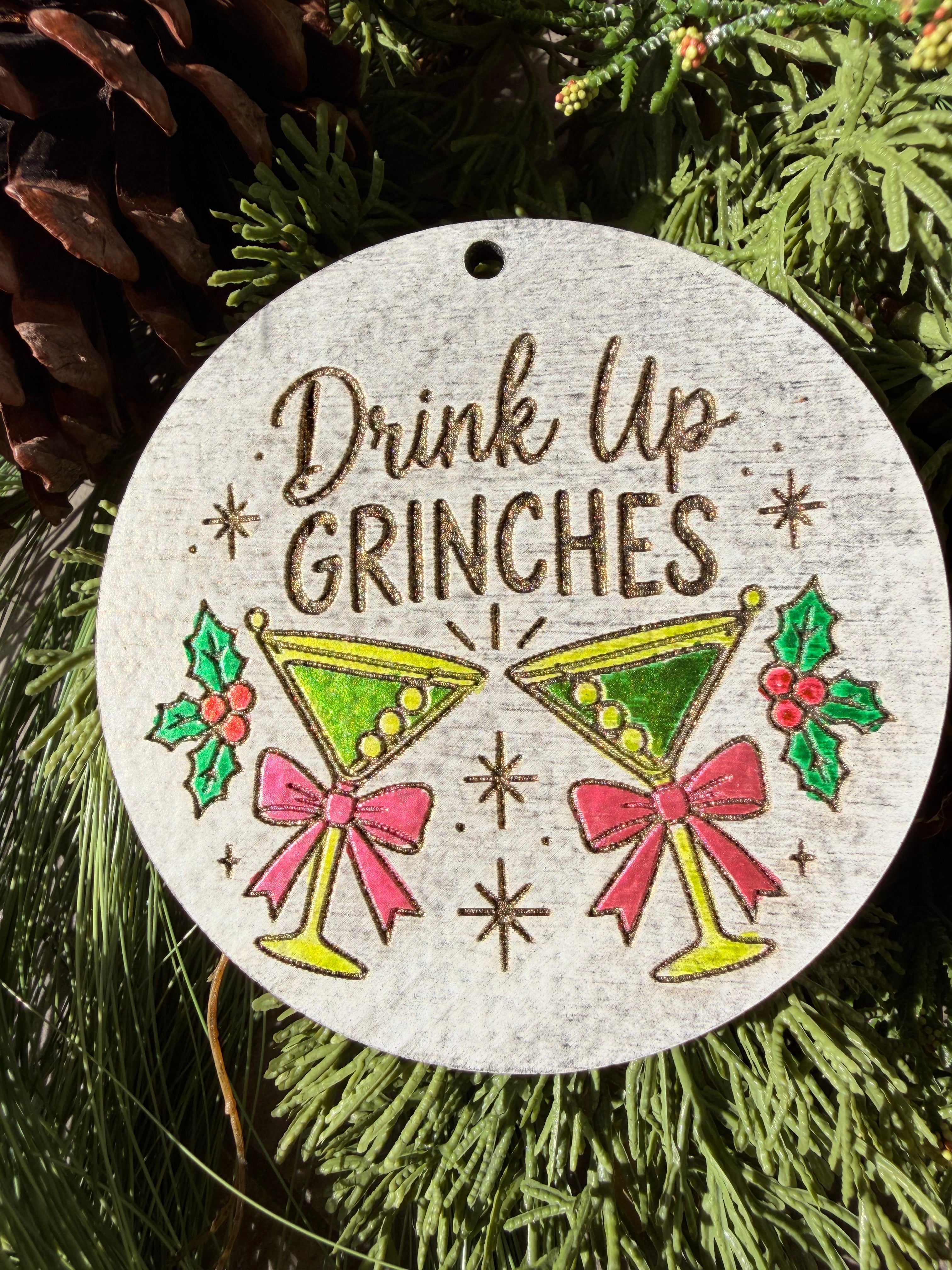 Finished hand-painted Drink Up, Grinches on evergreen greenery.