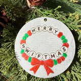 Finished hand-painted Merry Swiftmas Friendship Bracelet on evergreen greenery.