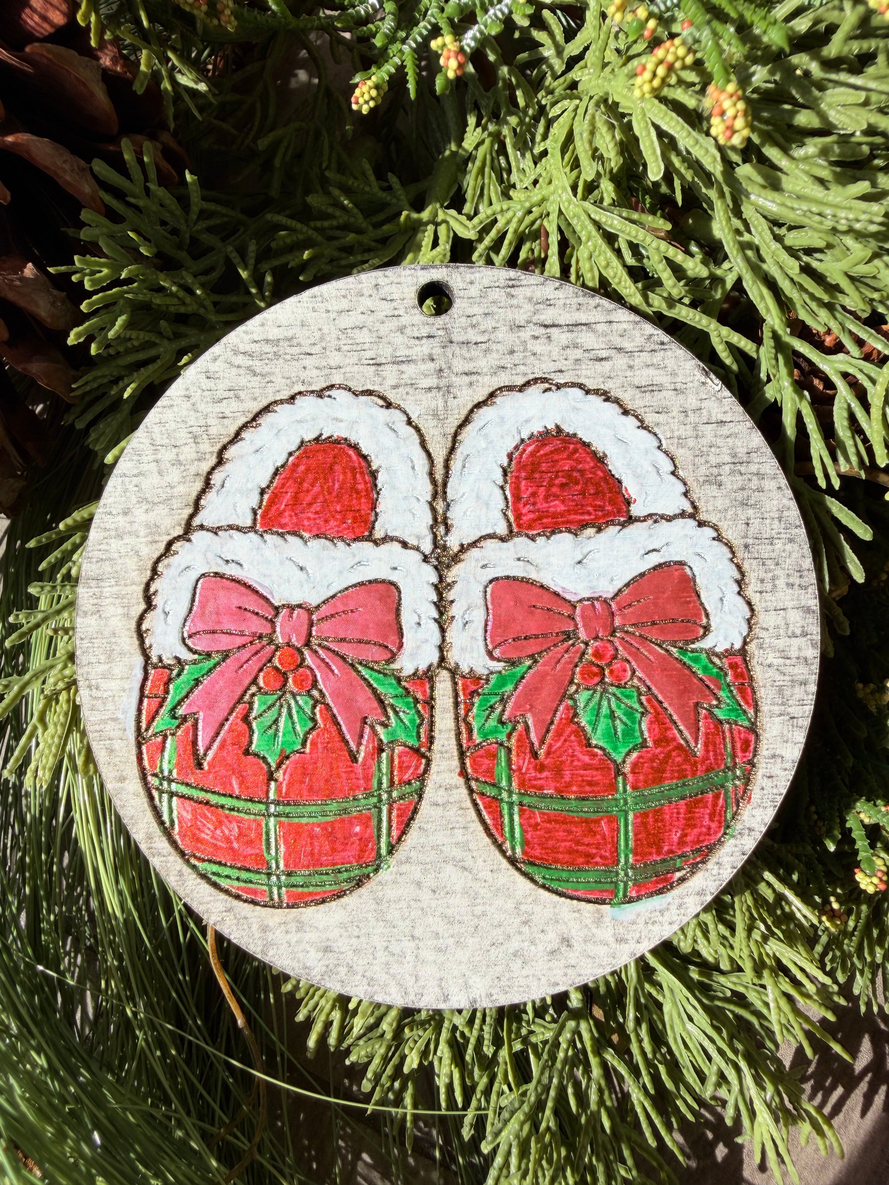 Finished hand-painted Cozy Plaid Slippers on evergreen greenery.