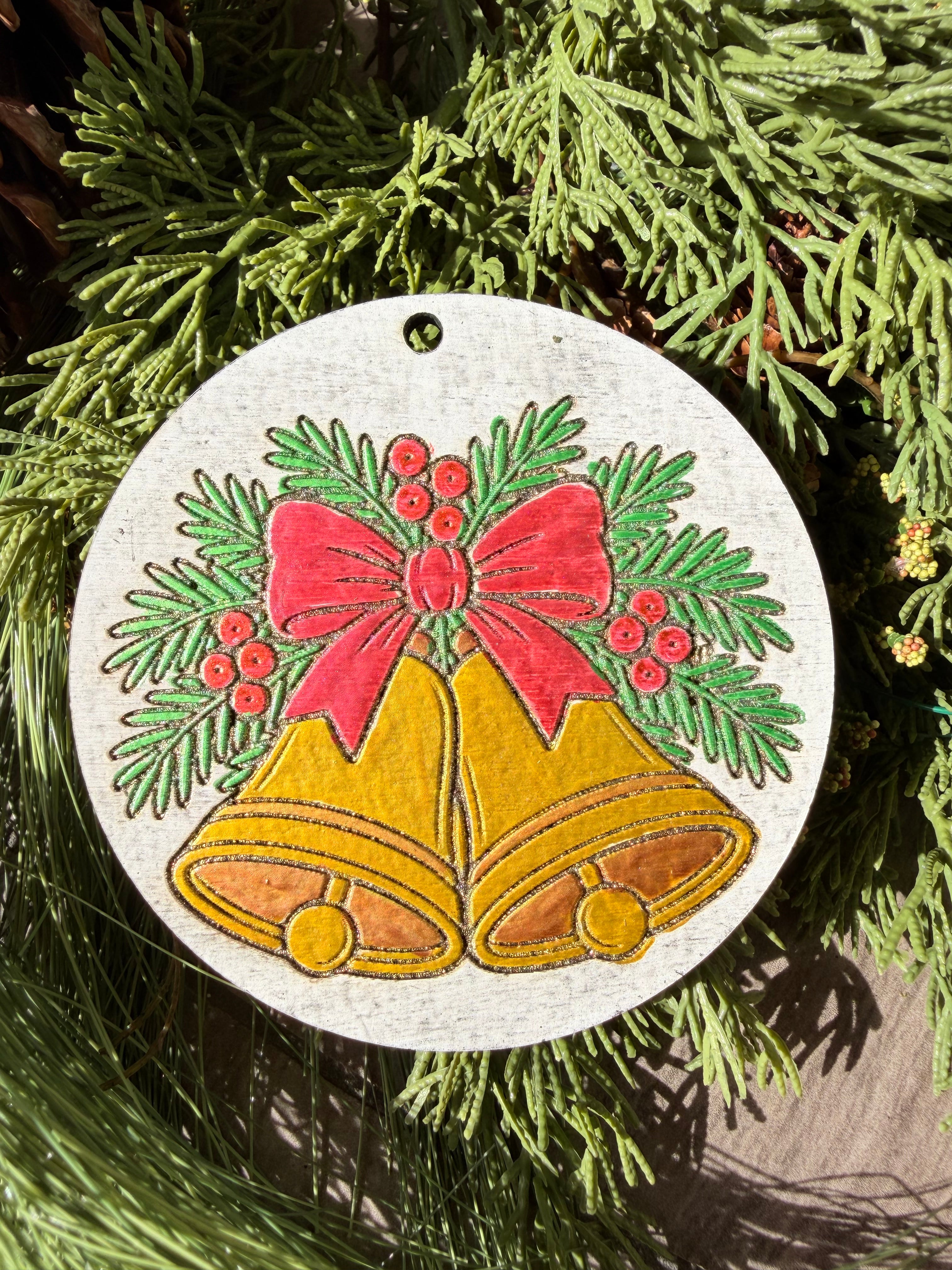 Finished hand-painted Golden Christmas Bells on evergreen greenery.