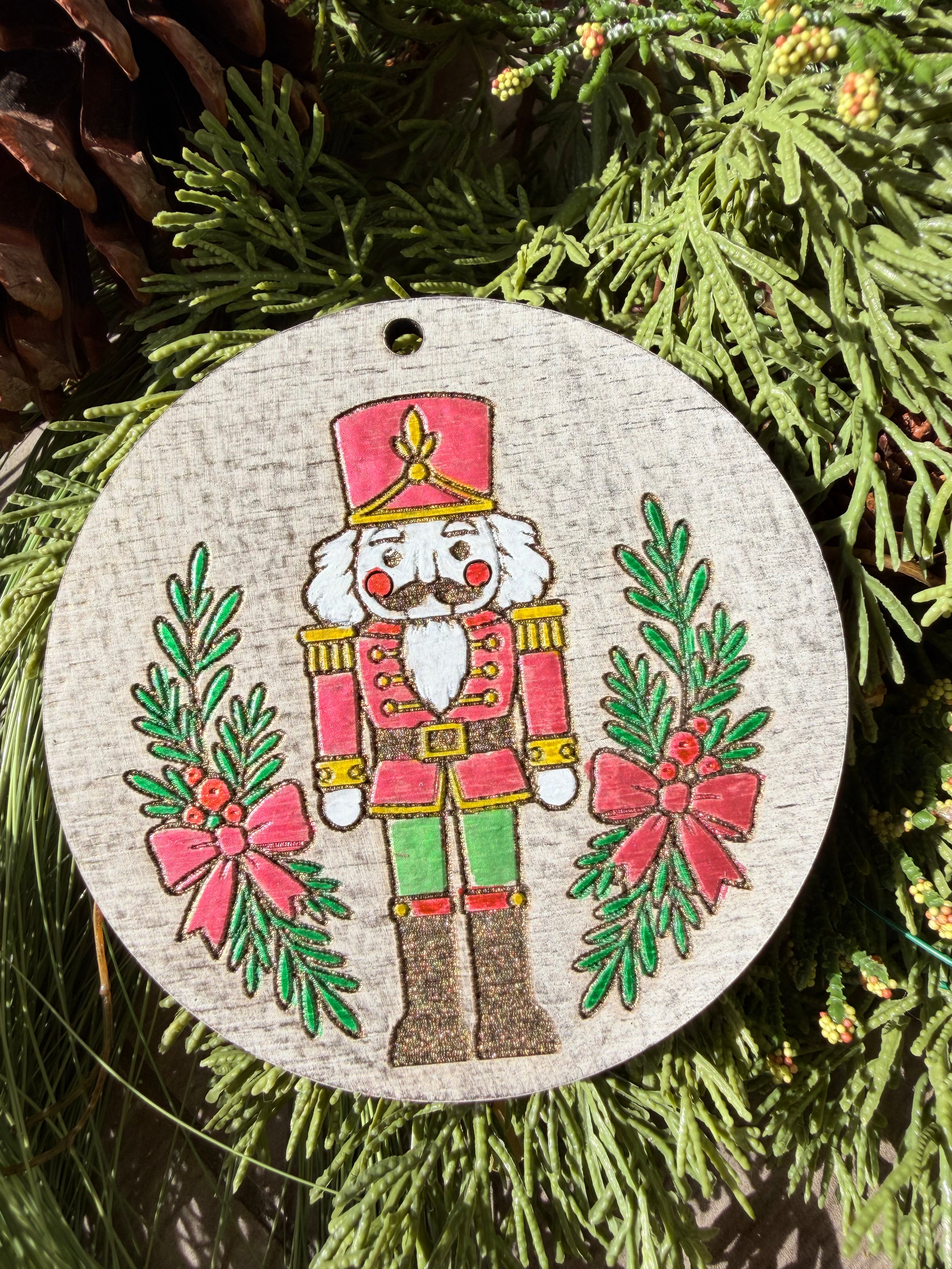 Finished hand-painted Pink & Green Nutcracker on evergreen greenery.