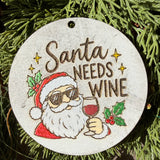 Finished hand-painted Santa Needs Wine on evergreen greenery.