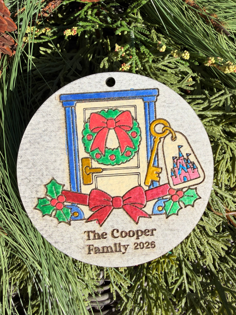 Finished hand-painted Resort Room Key Christmas Ornament on evergreen greenery. Name and year shown are sample personalization.