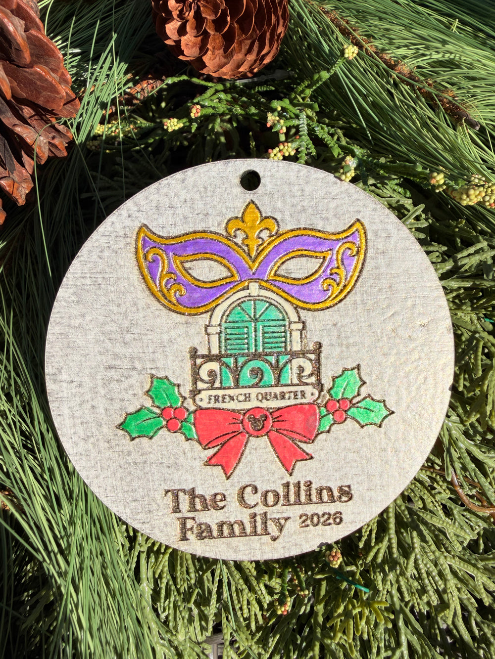 Finished hand-painted Port Orleans French Quarter Christmas Ornament on evergreen greenery. Name and year shown are sample personalization.