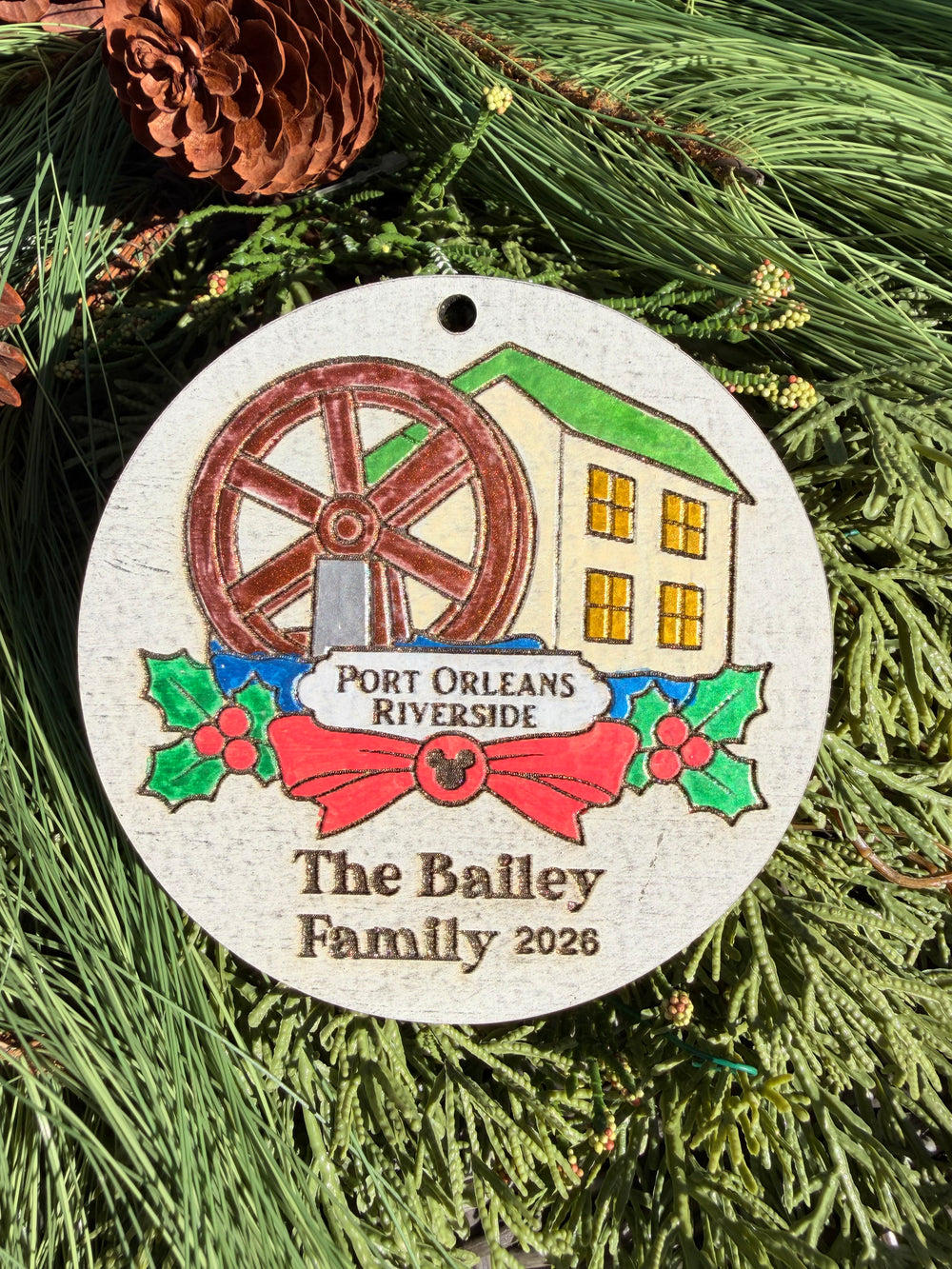 Finished hand-painted Port Orleans Riverside Christmas Ornament on evergreen greenery. Name and year shown are sample personalization.
