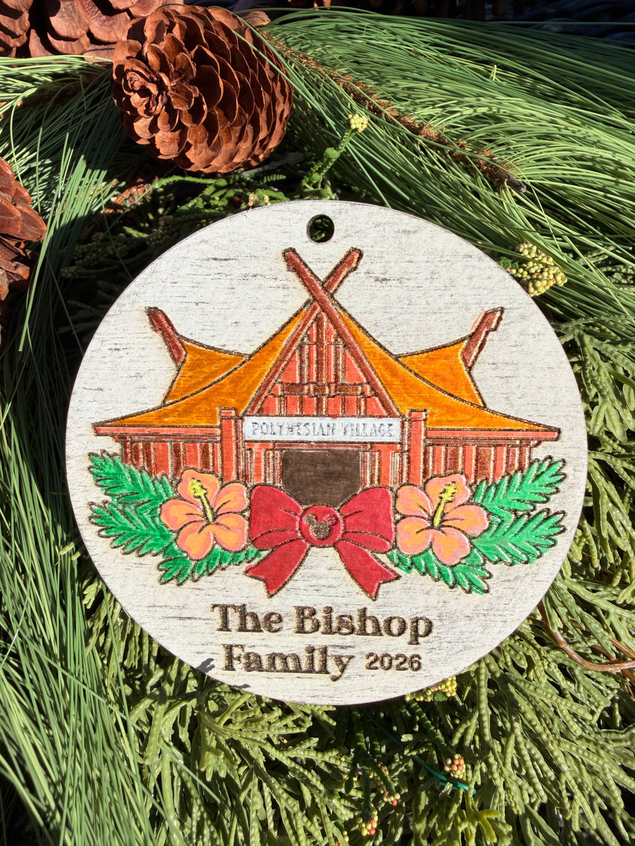 Finished hand-painted Polynesian Village Christmas Ornament on evergreen greenery. Name and year shown are sample personalization.