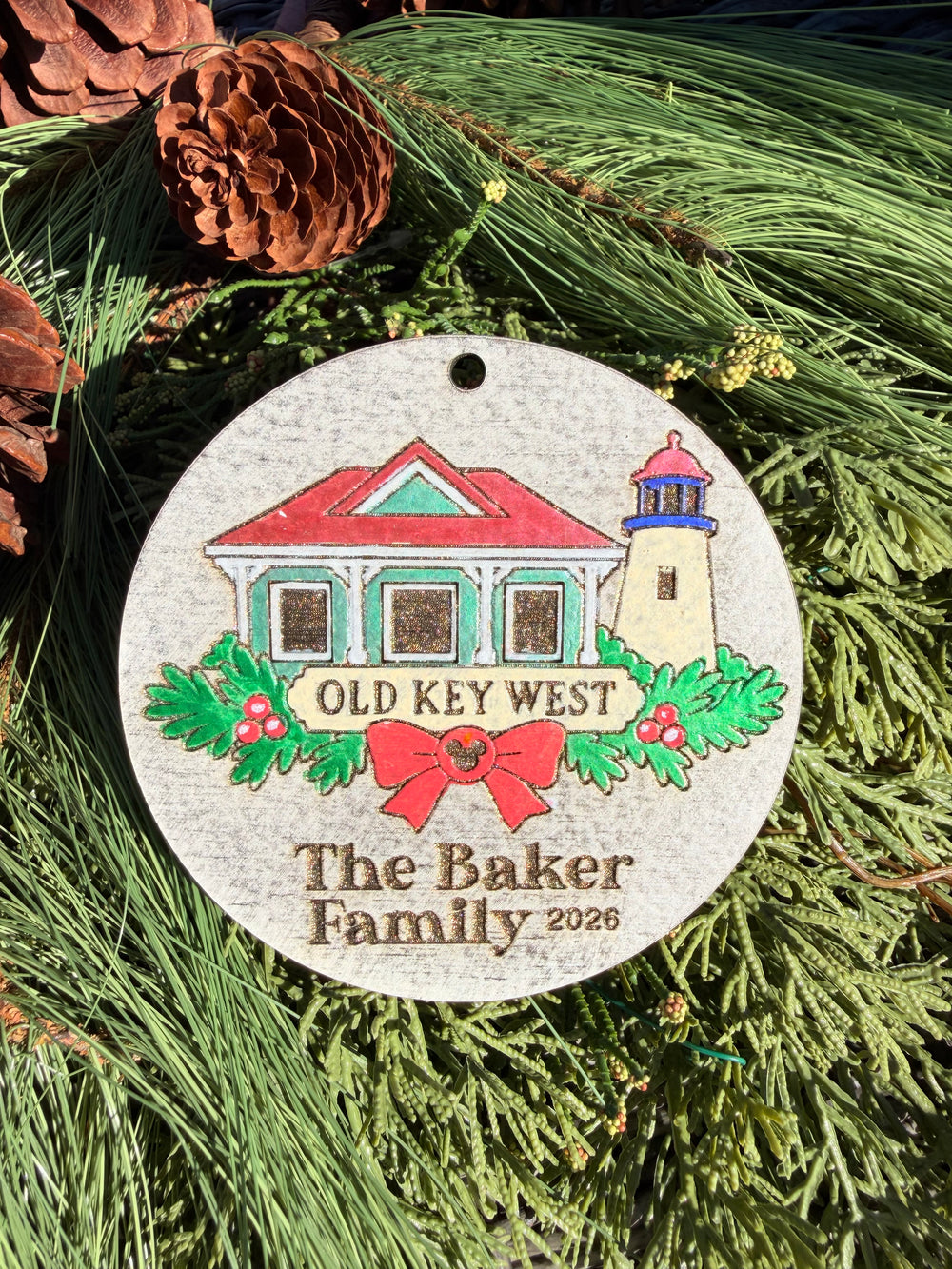 Finished hand-painted Old Key West Christmas Ornament on evergreen greenery. Name and year shown are sample personalization.