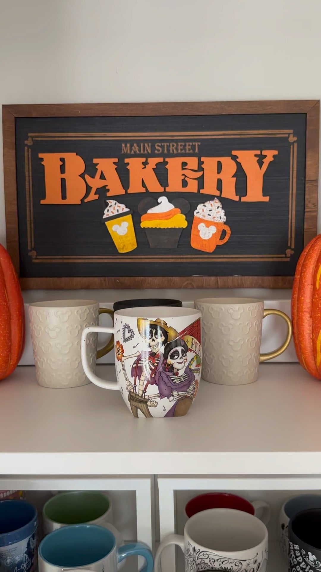 An orange-lettered Main Street Bakery framed sign above mugs in Justin’s home.